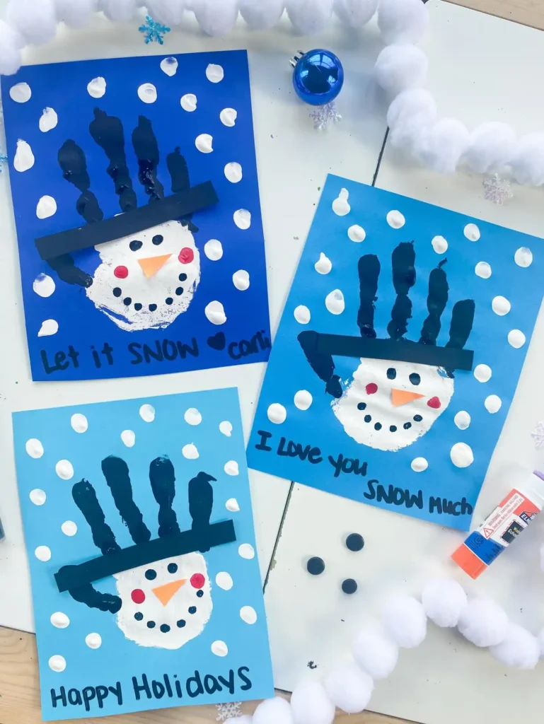 Baby christmas crafts: three blue handprint snowman cards with black handprint top hats