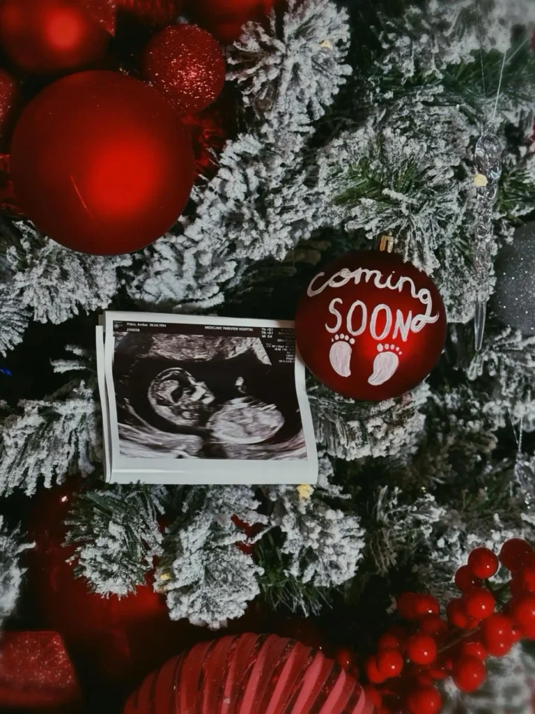 December pregnancy announcement with a red hand painted coming soon bauble and an ultrasound print on a flocked Christmas tree