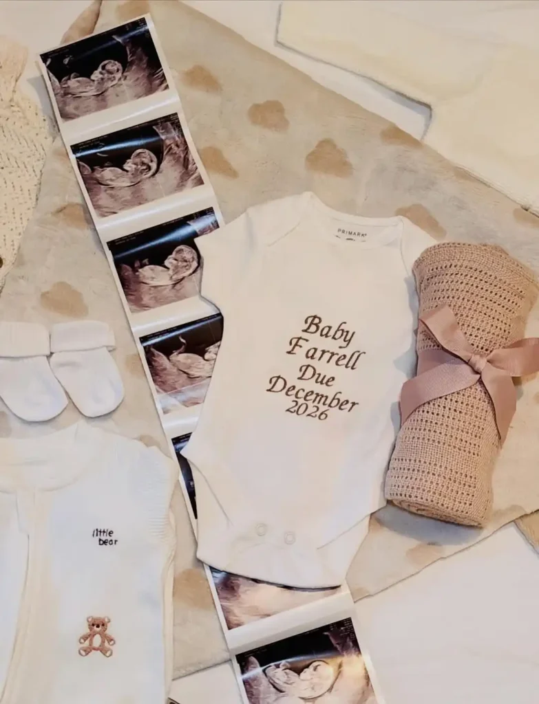 White baby bodysuit with a December 2026 due date beside an ultrasound strip and a rolled knit blanket