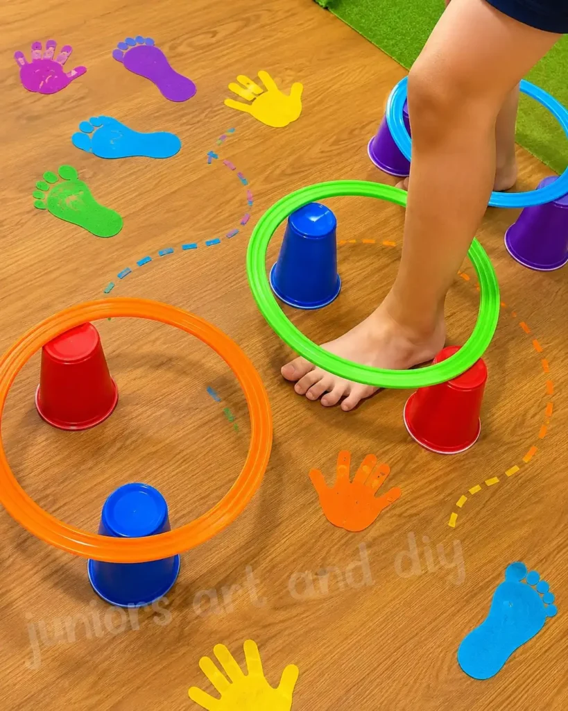 Child stepping through bright hoops resting on plastic cups among colorful cutout hands and feet on the floor