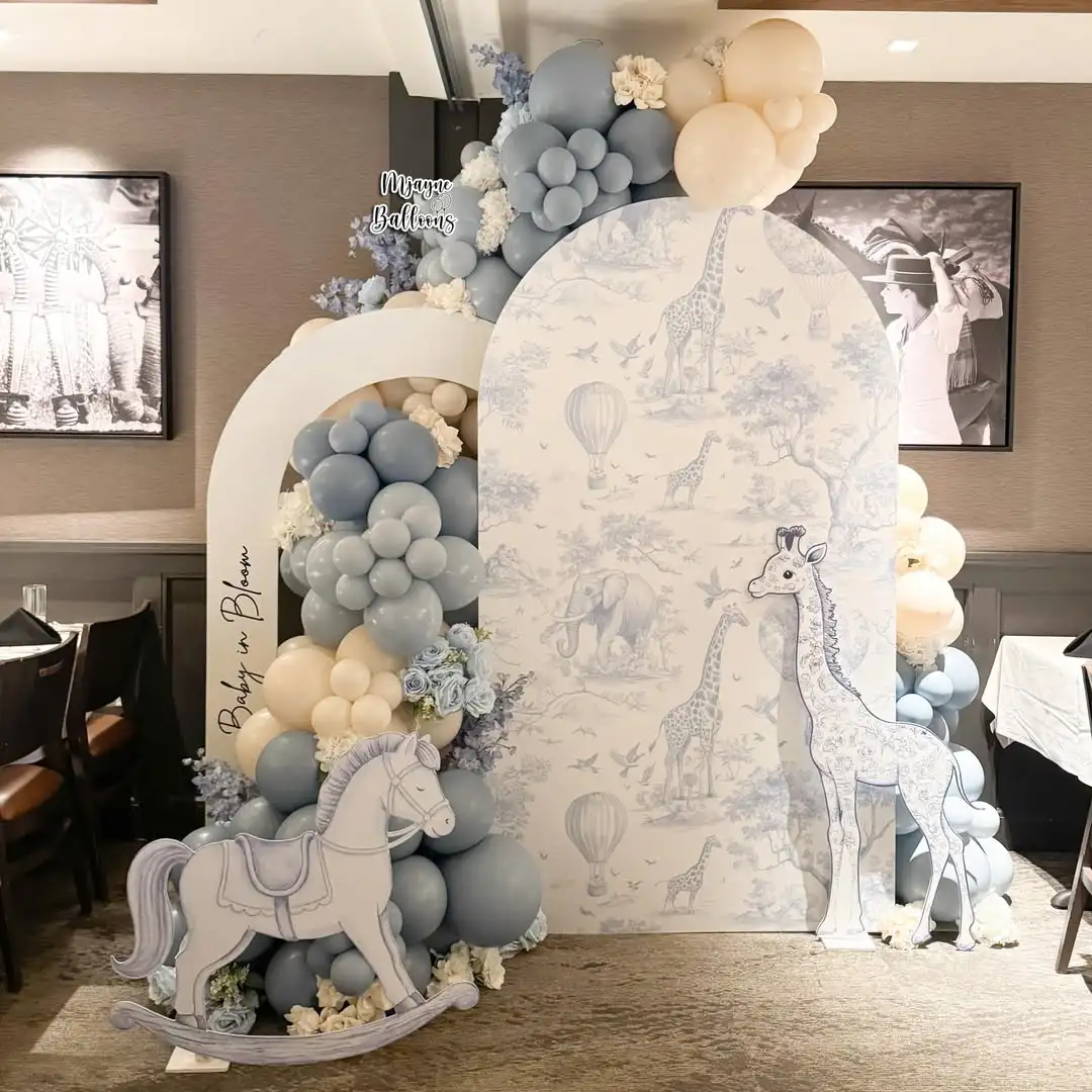 Blue, cream and white balloon arch with a toile giraffe backdrop and rocking horse cut-out at a baby shower