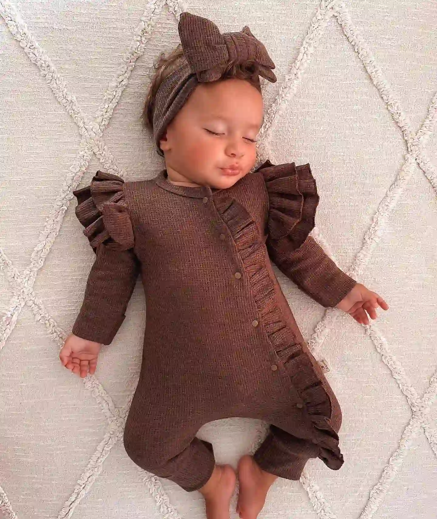 Sleeping baby in a brown waffle knit ruffle romper with a matching headband