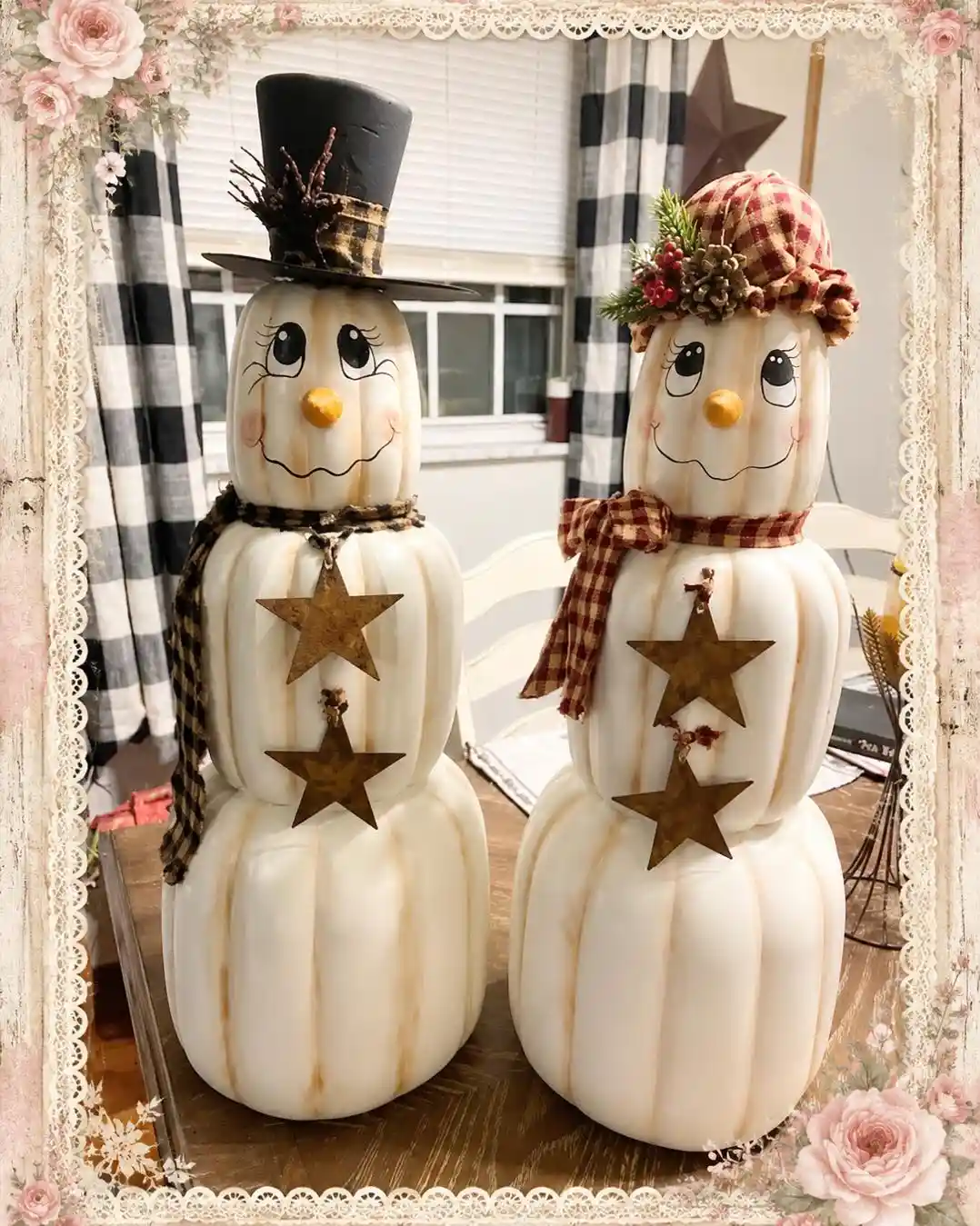 Two stacks of white ribbed pumpkins painted as snowmen with lashes, pink cheeks and yellow orange noses, one in a black top hat with a plaid band and one in a red check cap with greenery, with rusty metal stars hanging down the middle