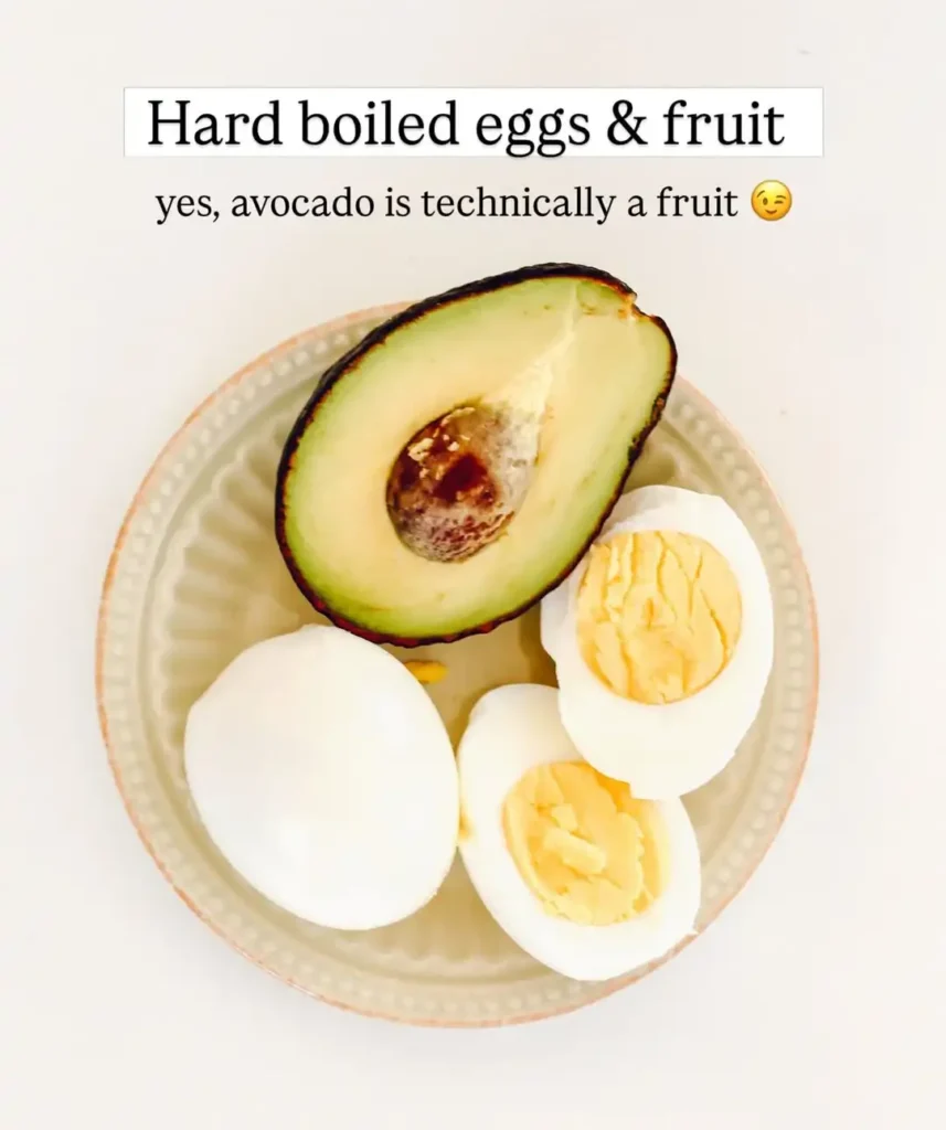 Small plate with half an avocado and halved hard boiled eggs on a white background