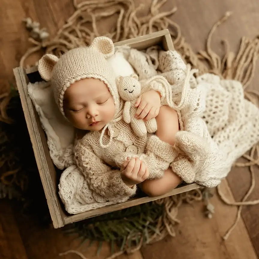 Baby in a Small Wooden Box With a Knit Bear Bonnet